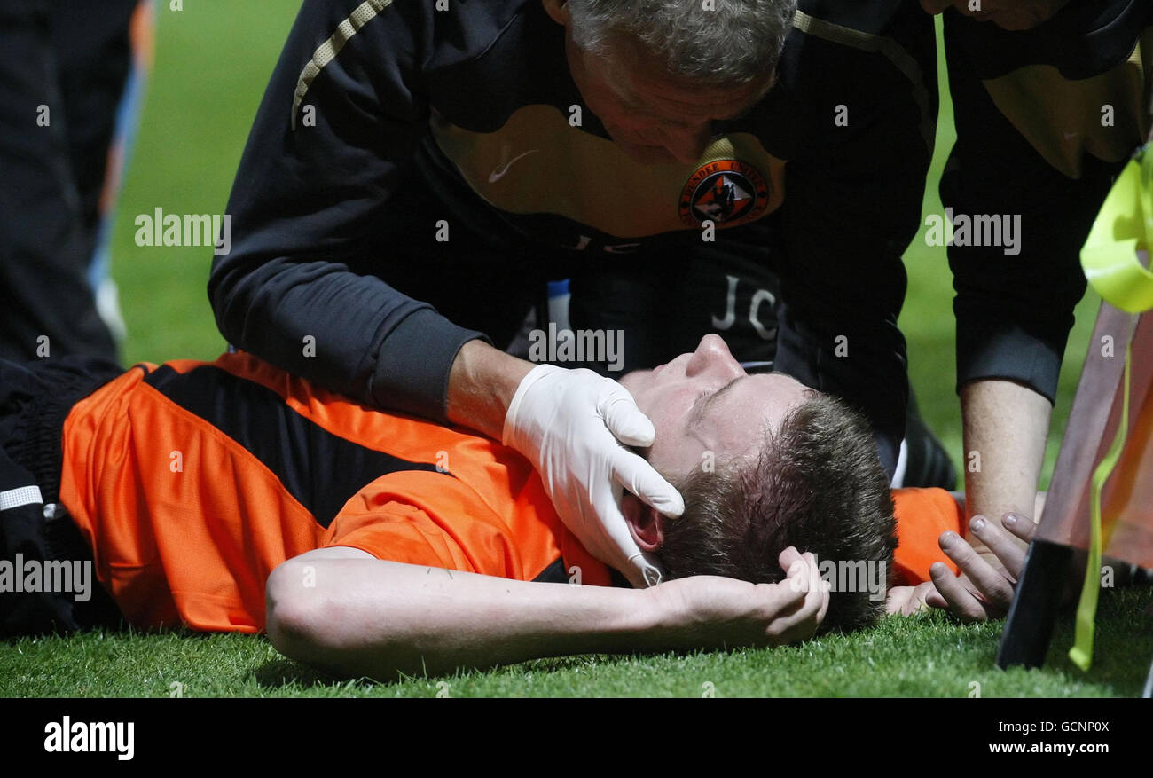 Paul Dixon di Dundee riceve il trattamento dopo aver collassato con un giocatore di Atene durante la finale di qualificazione della UEFA Europa League al Tannadice Park di Dundee. Foto Stock