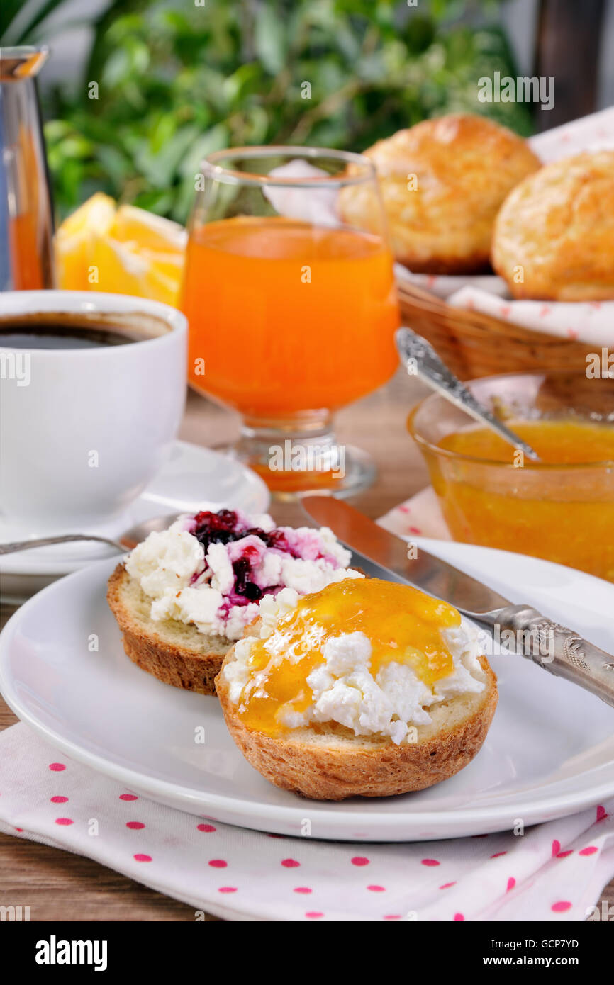 La prima colazione di bun con ricotta arancione e confettura di ciliegie Foto Stock