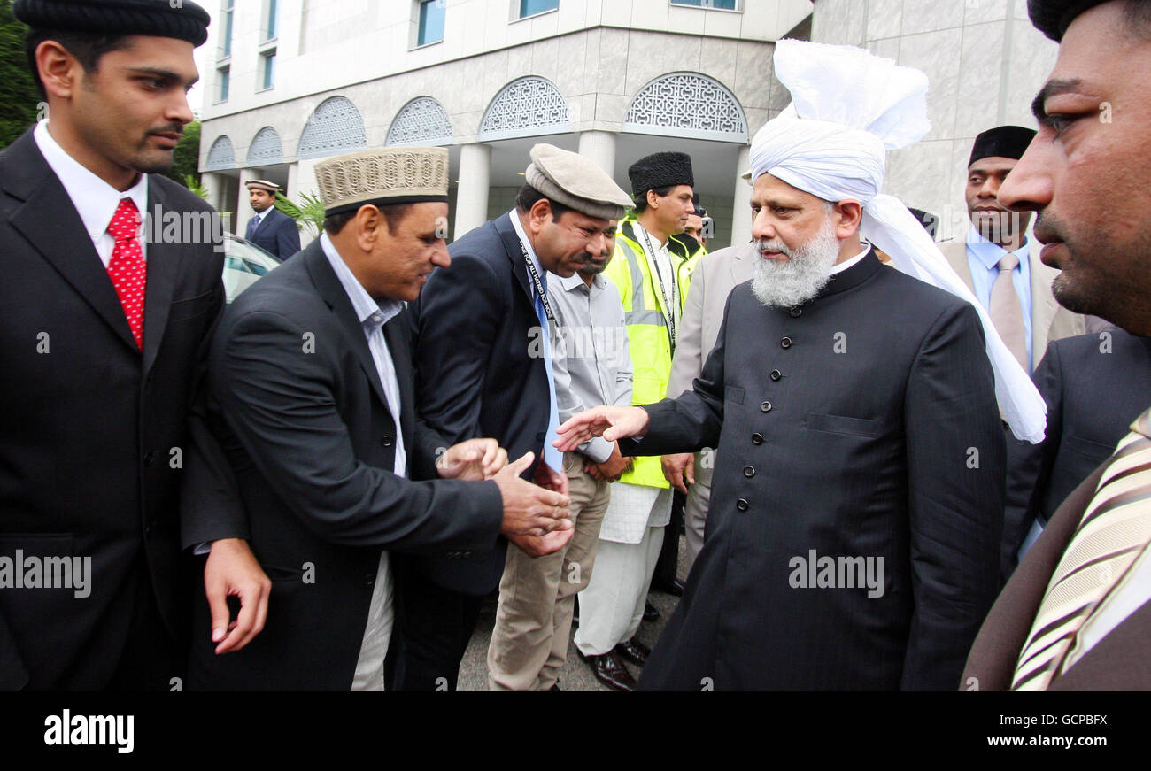 ahmadi musulmani alla Moschea di Baitul Futuh a Morden, Londra, la più grande moschea dell'Europa occidentale, dopo aver celebrato Eid con la preghiera, in cui oltre 10,000 fedeli hanno ricevuto un sermone Eid vivo dal capo mondiale della comunità musulmana Ahmadiyya, sua Santità, Hadhrat Miza Masroor Ahmad, (a destra), indossando un turbante. Foto Stock