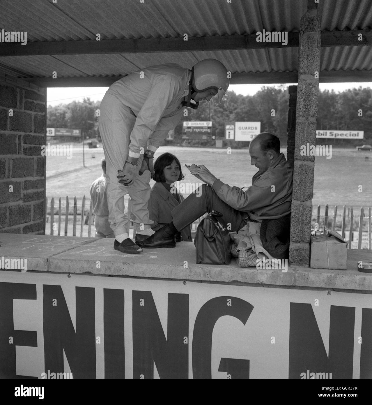 Stirling Moss (seduto) e sua moglie Elaine, con Trevor Taylor, il pilota di 27 anni di Rotherham, poco prima dell'incidente di quest'ultimo quando si pratica per il Gran Premio d'Europa sul circuito Brands Hatch di Kent. Foto Stock