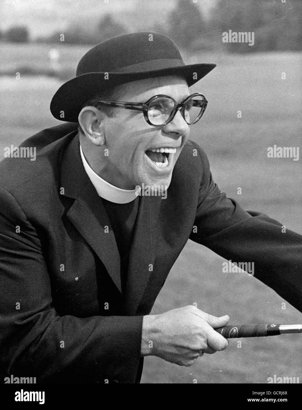 Il comico Norman Wisdom, vestito da clergista, nel suo nuovo film "The Early Bird" in cui Norman è un milkman coinvolto in una guerra di erba sintetica con un altro caseificio. Le riprese sono in corso presso i Pinewood Studios nel Buckinghamshire. Foto Stock