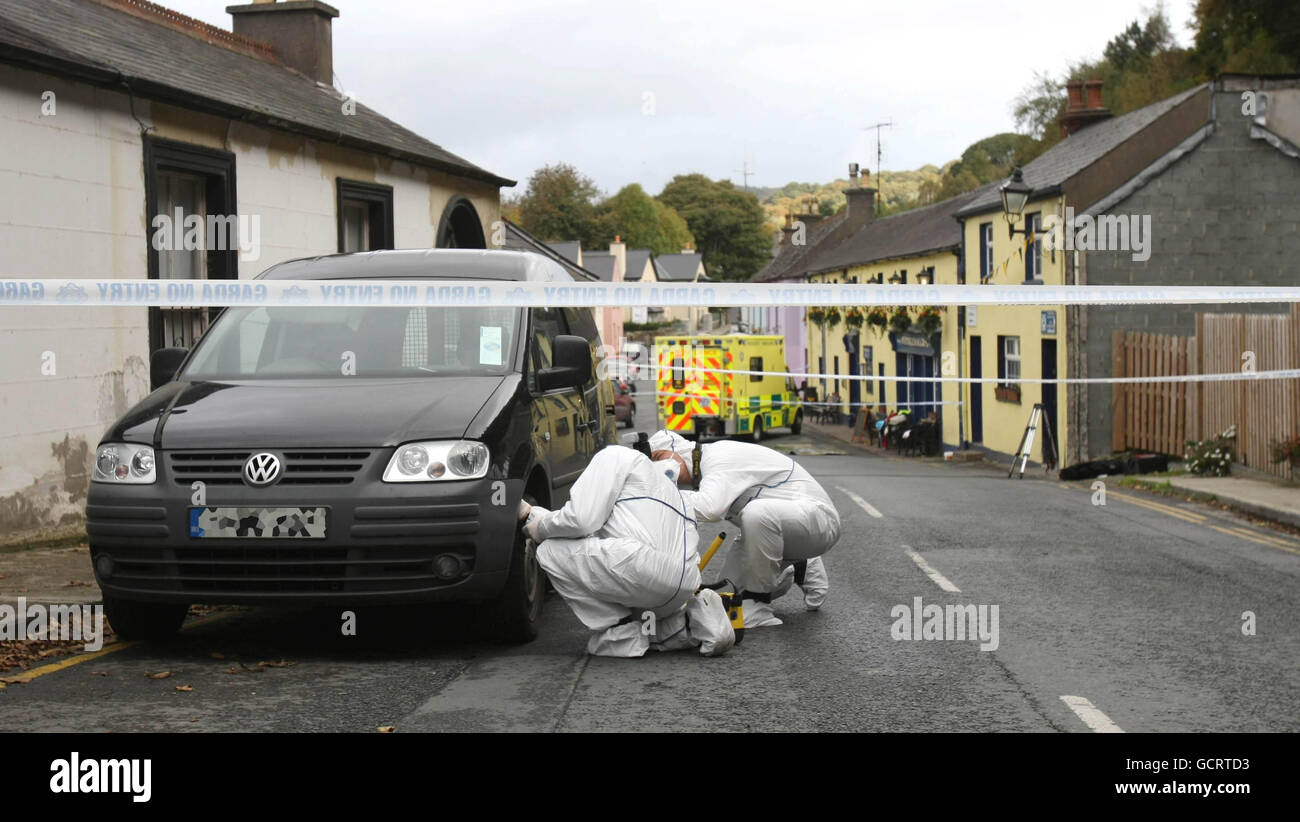 Scene di ufficiali del crimine esaminano un furgone vicino dove un uomo di 48 anni è stato trovato morto nella strada fuori il pub di Fitzgerald che è stato reso famoso nello spettacolo televisivo Ballykissangel, sulla strada principale in Avoca, Co Wicklow. Foto Stock