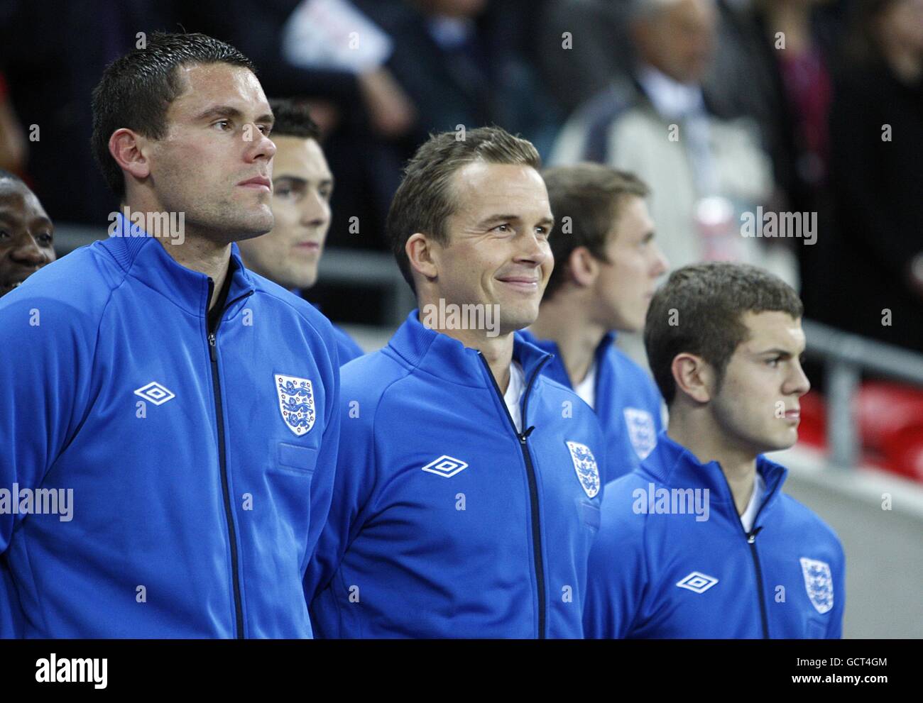 Kevin Davies (centro) in Inghilterra inizia la partita sulla panchina accanto a ben Foster (a sinistra) e Jack Wilshere (a destra). Foto Stock