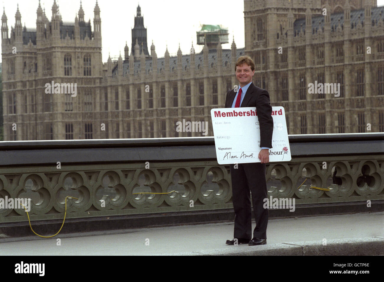 L'ex deputato conservatore Alan Amos si trova sul ponte di Westminster, accanto alle Camere del Parlamento, con la sua tessera di appartenenza al partito laburista. Egli ha cambiato fedeltà al partito laburista dopo aver accusato i Tory di essere un 'partito di attacco straniero e di odiazione minoritaria?. Il sig. Amos si è dimesso in qualità di deputato per Hexham nel 1992 a seguito del suo arresto per presunta indecenza a Hamstead Heath. Foto Stock