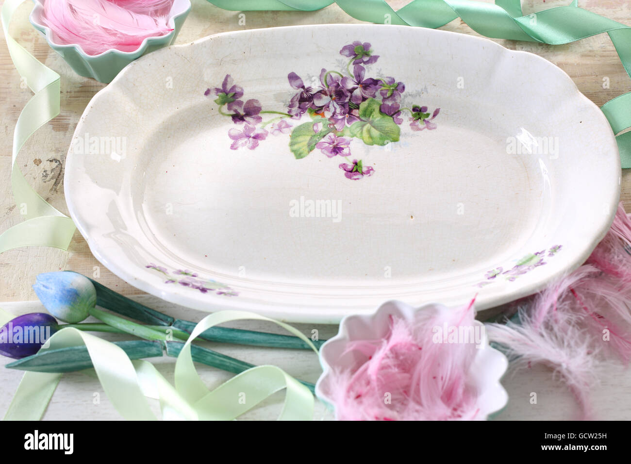 Piastra con fiori dipinti su sfondo beige con nastro verde e boscoso tulip e le penne degli uccelli. Foto Stock