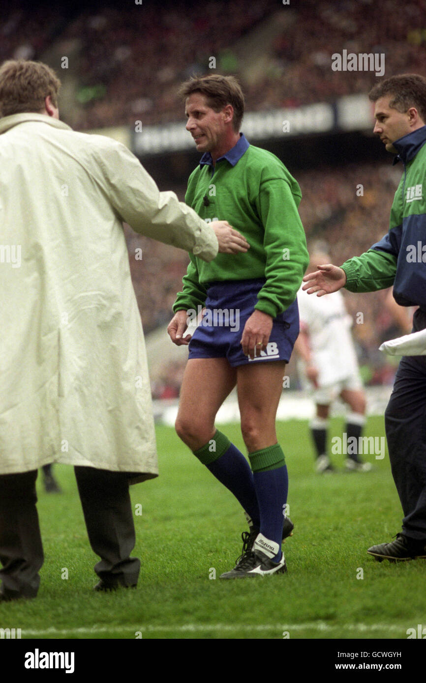 L'arbitro Colin Hawke (dalla Nuova Zelanda) è guidato fuori dal campo dal linesman Chris White (r) e Nick Bunting (l) dopo aver strappato un muscolo di vitello. Fu sostituito da Jim Fleming (non raffigurato) della Scozia. Foto Stock