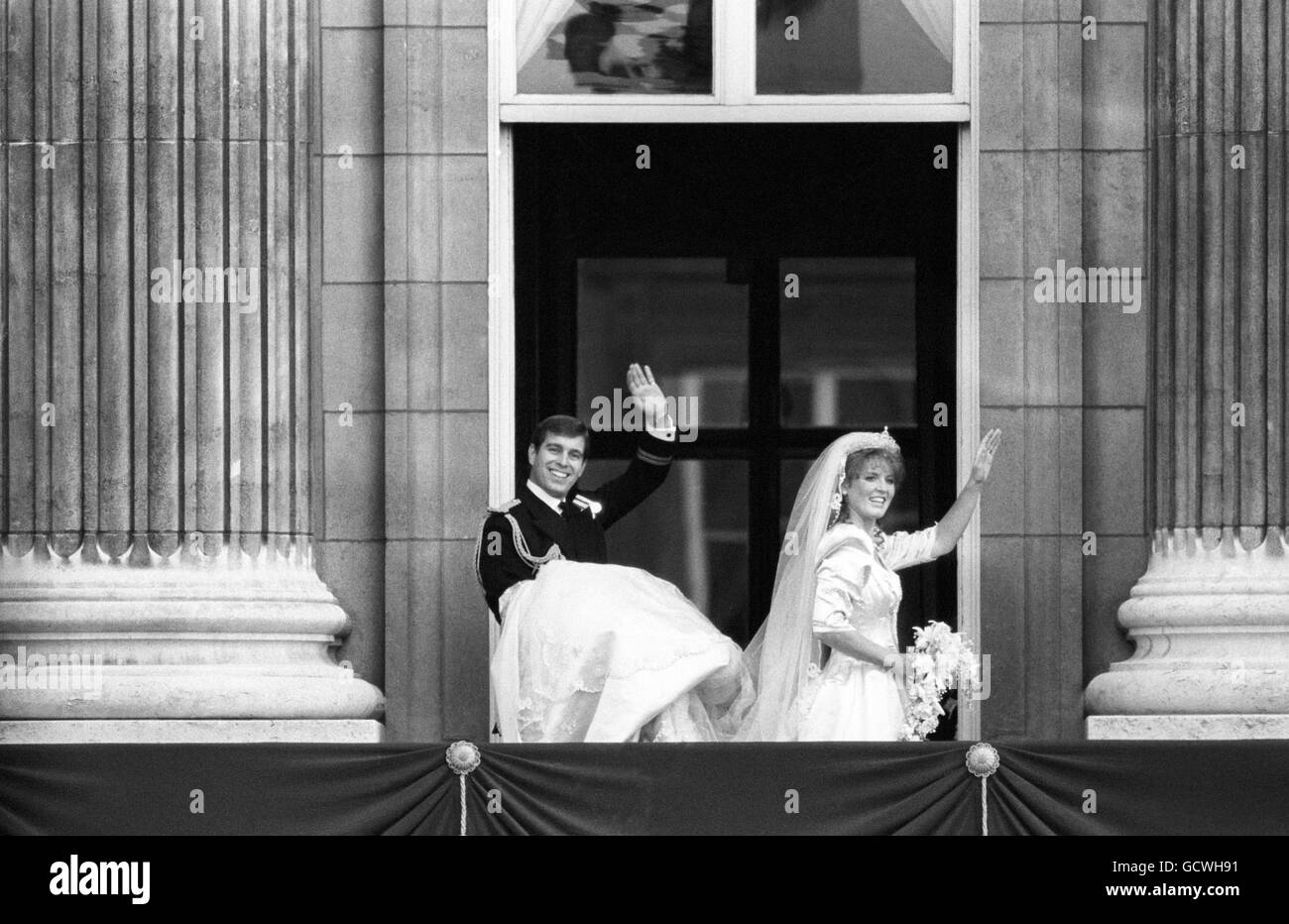 Il Duca e la Duchessa di York si arenano alla folla dal balcone di Buckingham Palace, mentre il Duca tiene il treno dell'abito da sposa della sua sposa. Foto Stock