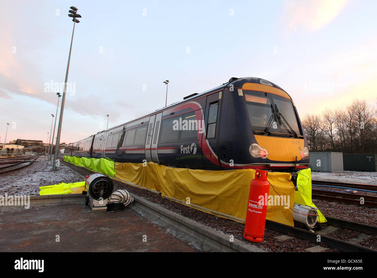 Il personale di Scotrail regola le battiscopa mentre le soffianti a gas aiutano a sbrinare il carro dei treni, poiché il nuovo ministro dei trasporti scozzese Keith Brown utilizza lo spray "Kill Frost", uno spray anti-ghiaccio che impedisce e facilita la rimozione del ghiaccio dal carro di un treno durante una visita al deposito Eastfield di ScotRail Glasgow. Foto Stock