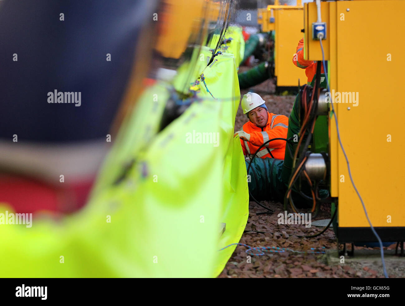 Il personale di Scotrail regola le battiscopa mentre le soffianti a gas aiutano a sbrinare il carro dei treni, poiché il nuovo ministro dei trasporti scozzese Keith Brown utilizza lo spray "Kill Frost", uno spray anti-ghiaccio che impedisce e facilita la rimozione del ghiaccio dal carro di un treno durante una visita al deposito Eastfield di ScotRail Glasgow. Foto Stock