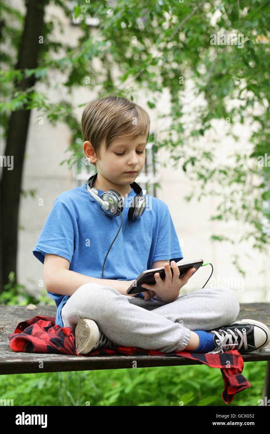 Il ragazzo ascolta la musica al di fuori del parco Foto Stock