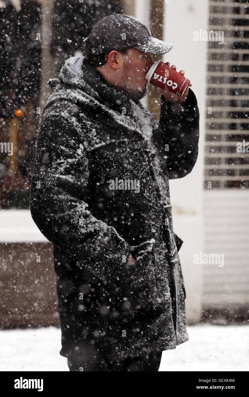 Un uomo ama una bevanda calda a Edimburgo mentre la neve e le condizioni di ghiaccio colpiscono la Scozia centrale. Foto Stock