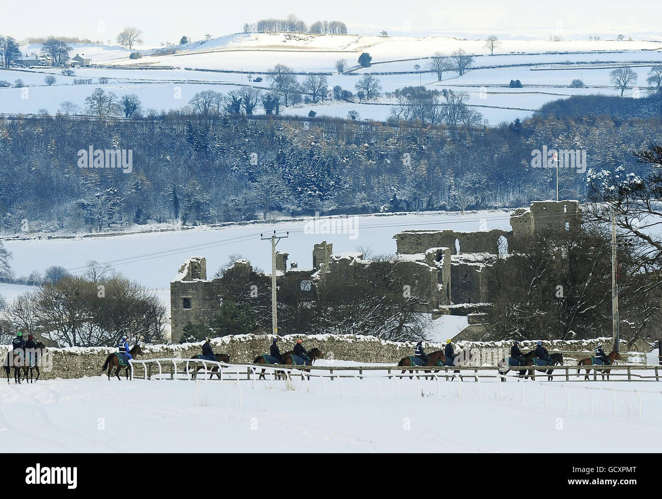 I cavalli si allenano nella neve sulle galoppe mentre attraversano il castello di Middleham. Foto Stock