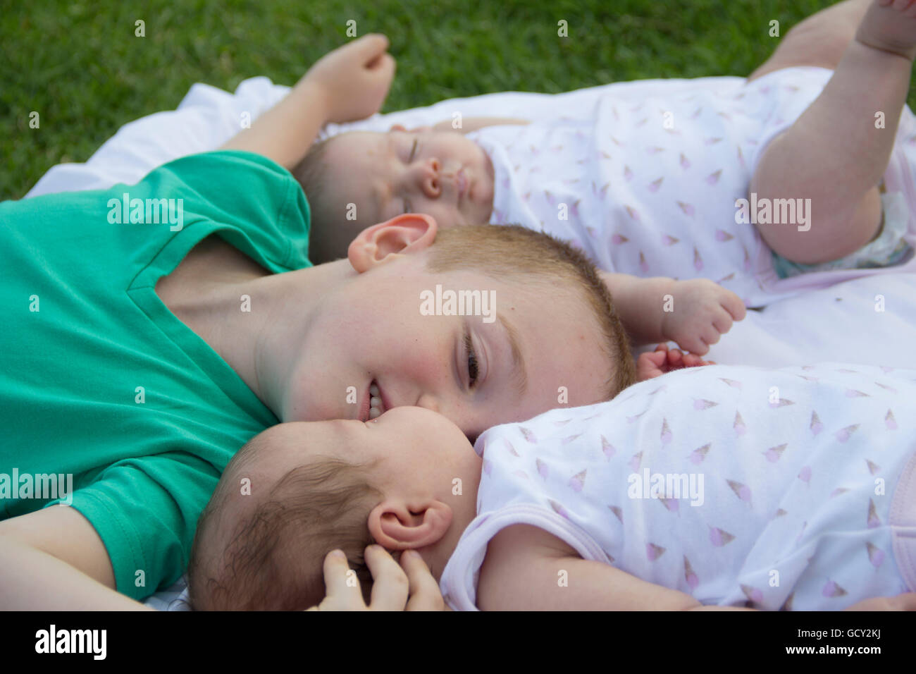 Felice fratello baciare una delle sue sorelle gemelle in posizione di parcheggio Foto Stock