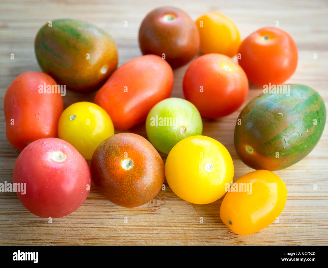 Una bella e coloratissima serie di estate varietà di pomodoro su una superficie di bambù. Foto Stock