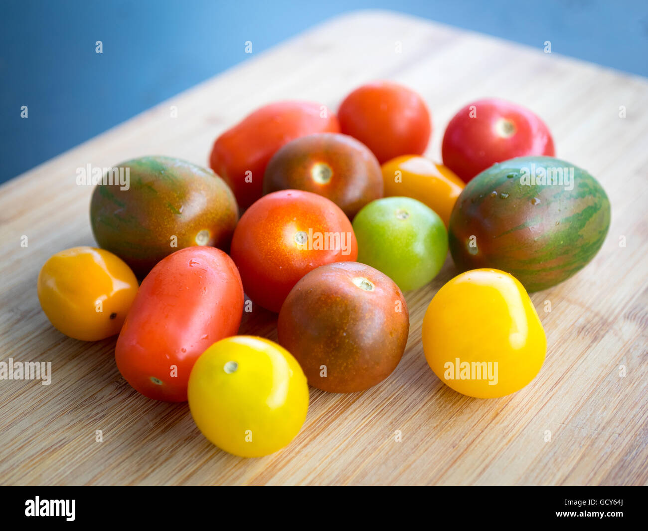 Una bella e coloratissima serie di estate varietà di pomodoro su una superficie di bambù. Foto Stock