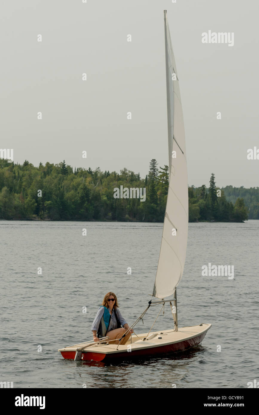 Una donna si siede su una piccola barca a vela in un lago Ontario, Canada Foto Stock