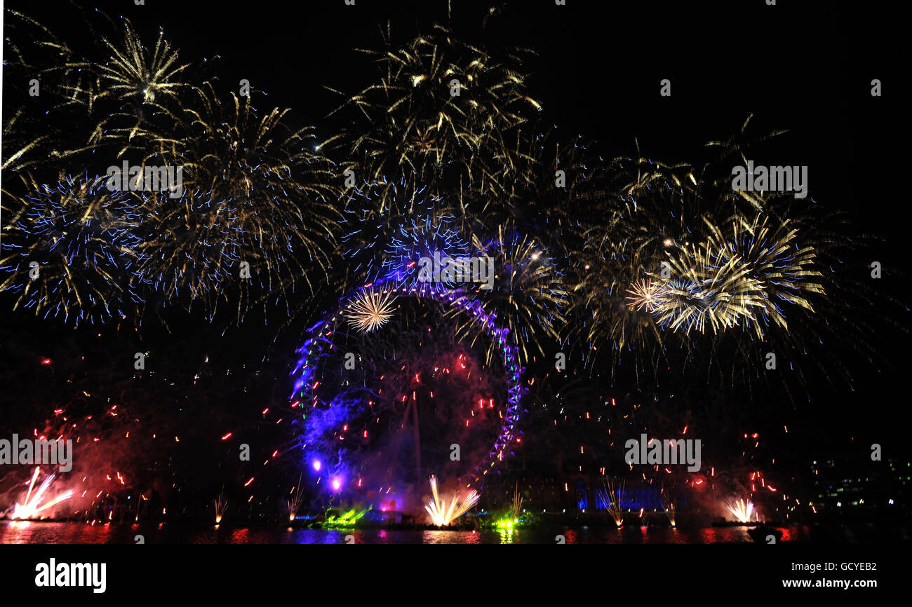 Fuochi d'artificio illuminano il cielo sul London Eye durante le celebrazioni di Capodanno a Londra. Foto Stock