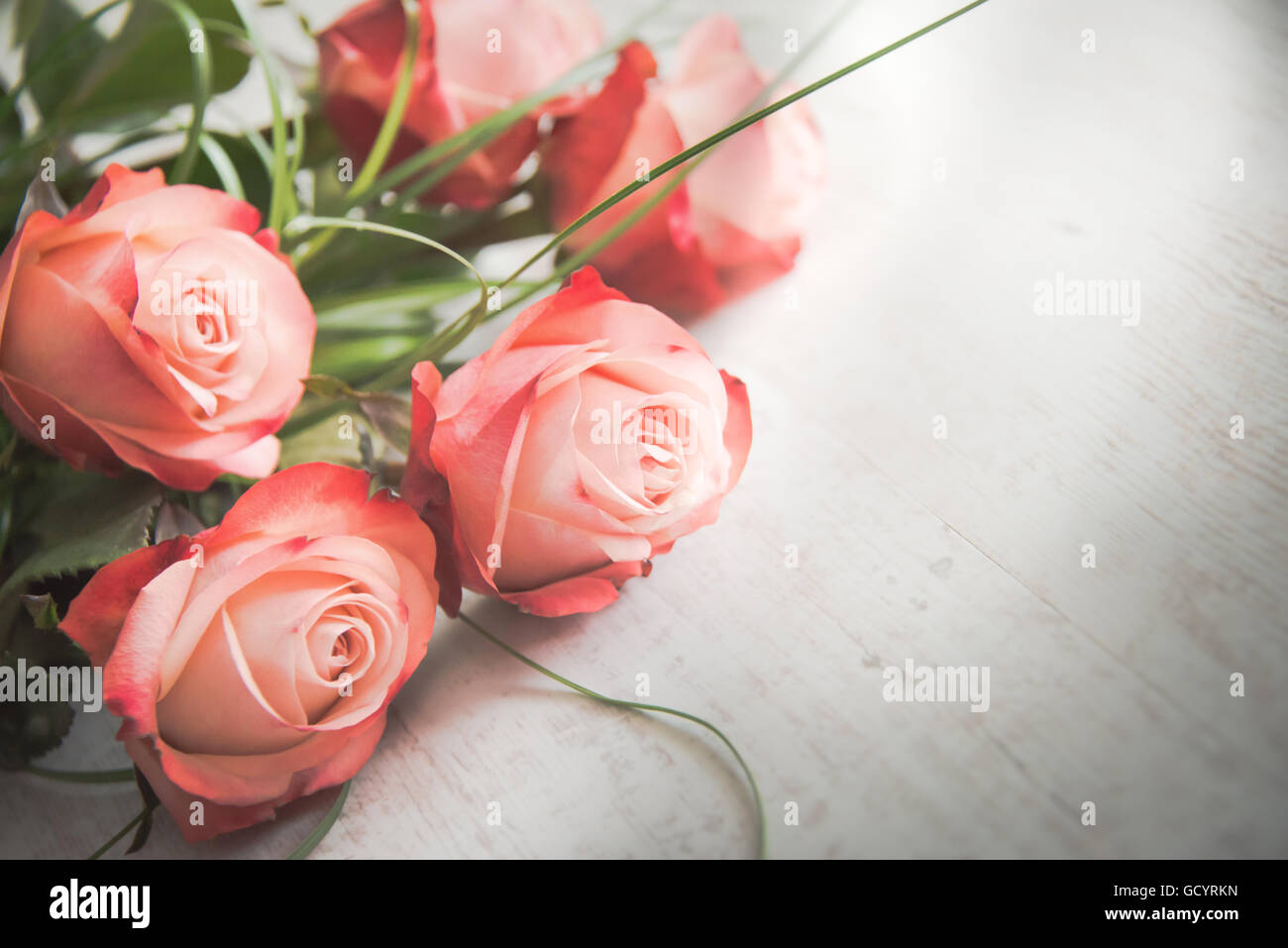 Un mazzo di rose su di un legno bianco sfondo vecchio. In stile vintage. Foto Stock