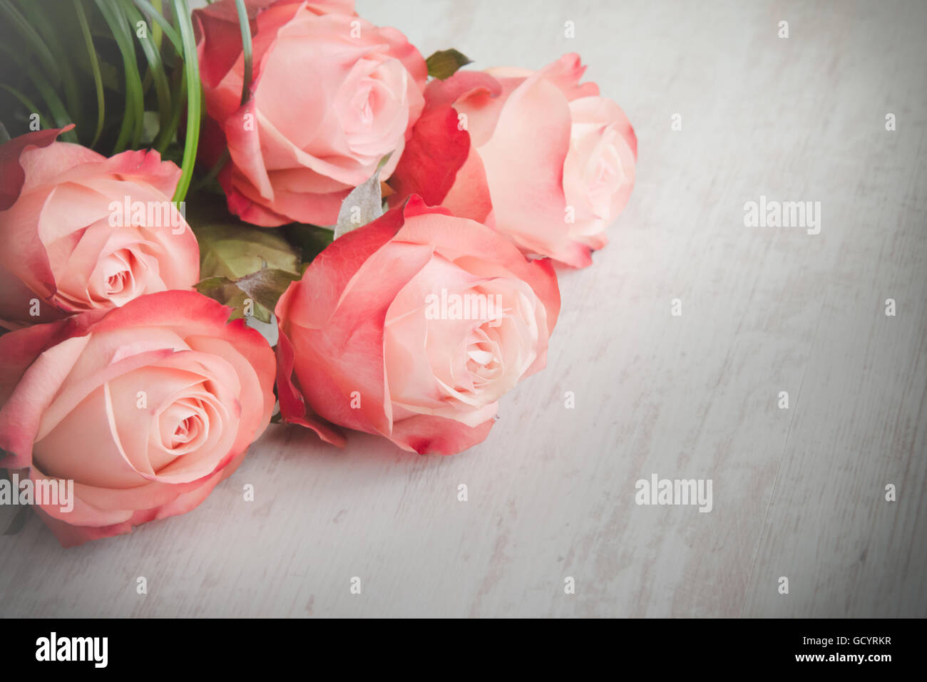 Un mazzo di rose su di un legno bianco sfondo vecchio. In stile vintage. Foto Stock