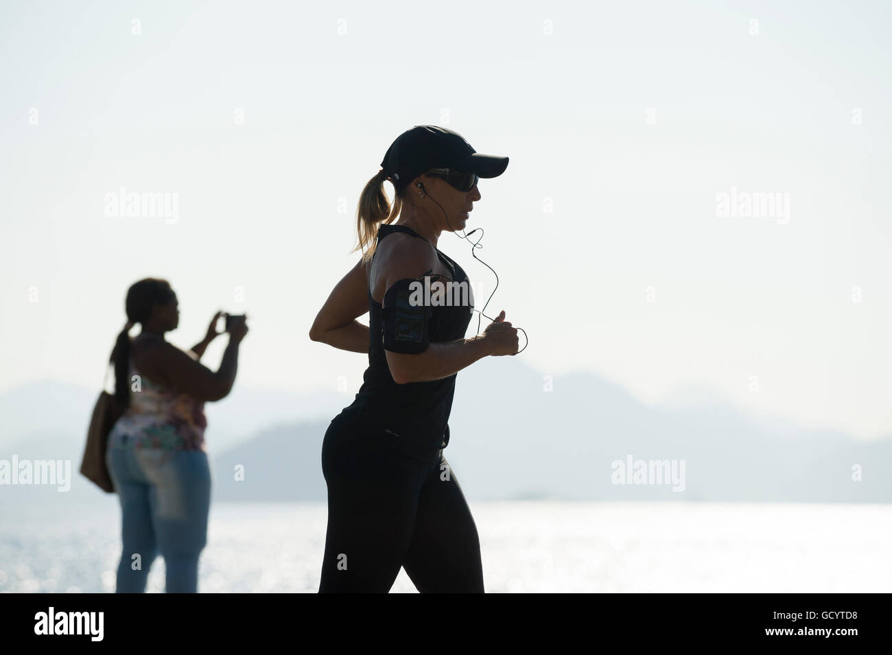 RIO DE JANEIRO - Aprile 3, 2016: Un pareggiatore passa in silhouette di fronte un mattino luminoso vista dalla spiaggia di Copacabana. Foto Stock