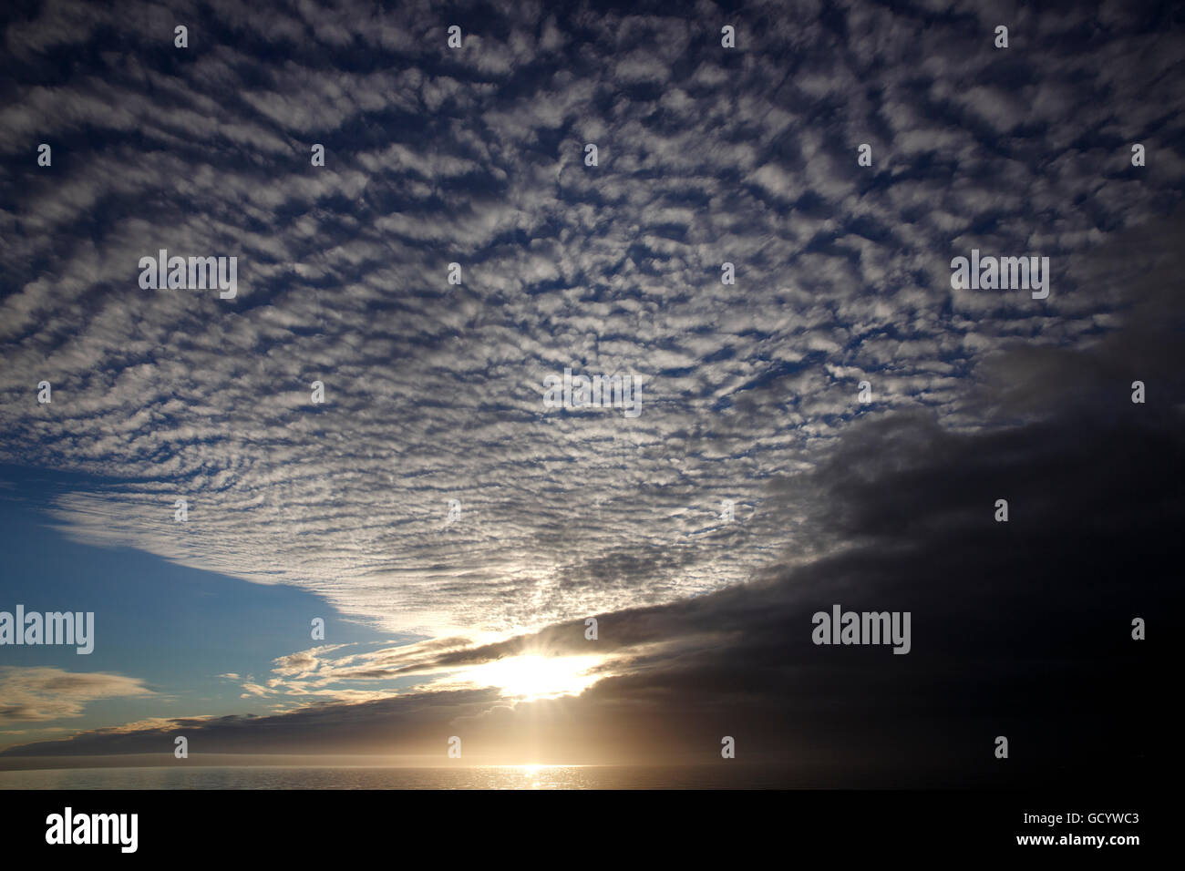 Il sole di mezzanotte dietro il cloud bank al largo della costa occidentale della Groenlandia Foto Stock