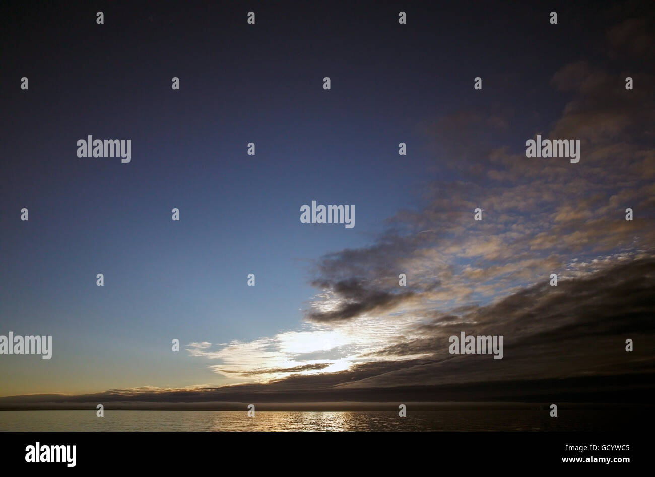Il sole di mezzanotte dietro il cloud bank al largo della costa occidentale della Groenlandia Foto Stock
