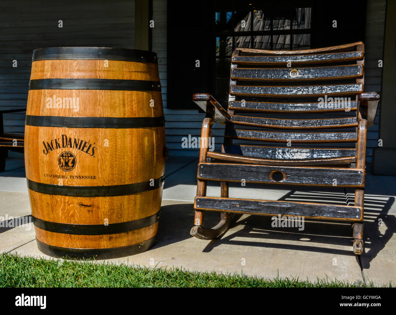 Legno nero stile tornio sedia a dondolo sul portico lungo il lato di un autentica botte di rovere di Jack Daniel's n. 7 Whiskey, Lynchburg, TN Foto Stock