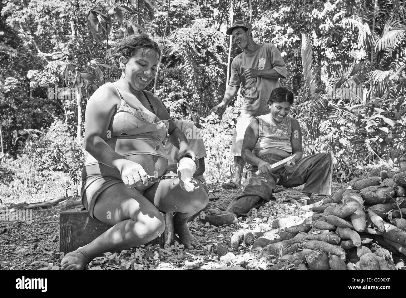 Immagine in bianco e nero di persone indigene peeling radici di manioca. Foto Stock