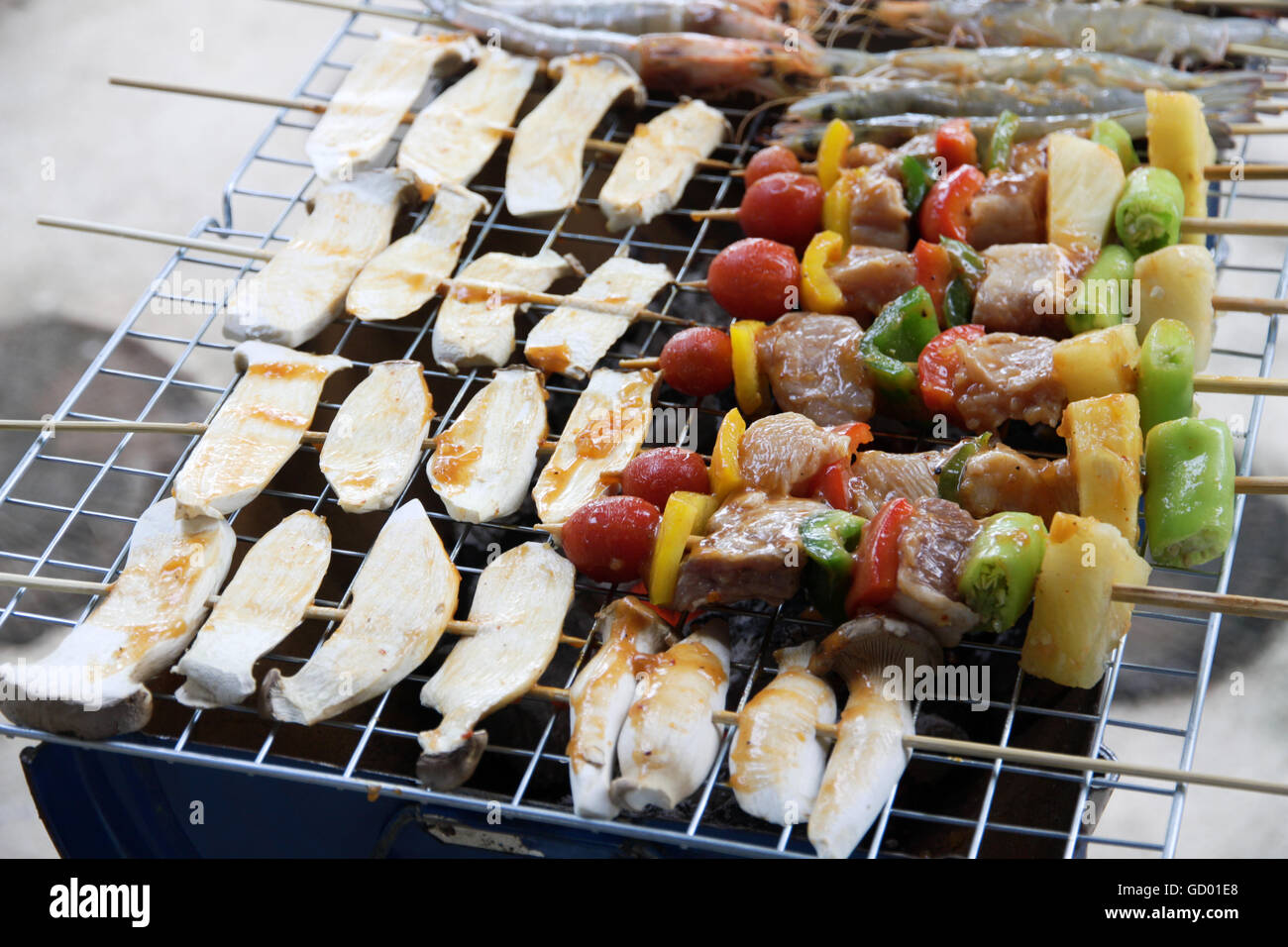 Pollo shish kebab sulla griglia per il barbecue in salsa su spiedini con pomodori e peperoni. gamberi e funghi eringii grill. Foto Stock