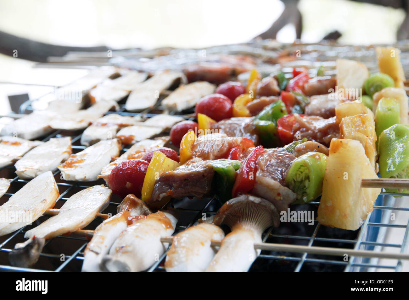 Pollo shish kebab sulla griglia per il barbecue in salsa su spiedini con pomodori e peperoni. gamberi e funghi eringii grill. Foto Stock