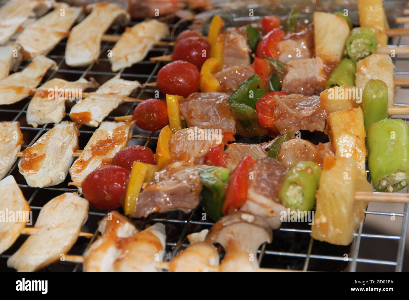 Pollo shish kebab sulla griglia per il barbecue in salsa su spiedini con pomodori e peperoni. gamberi e funghi eringii grill. Foto Stock