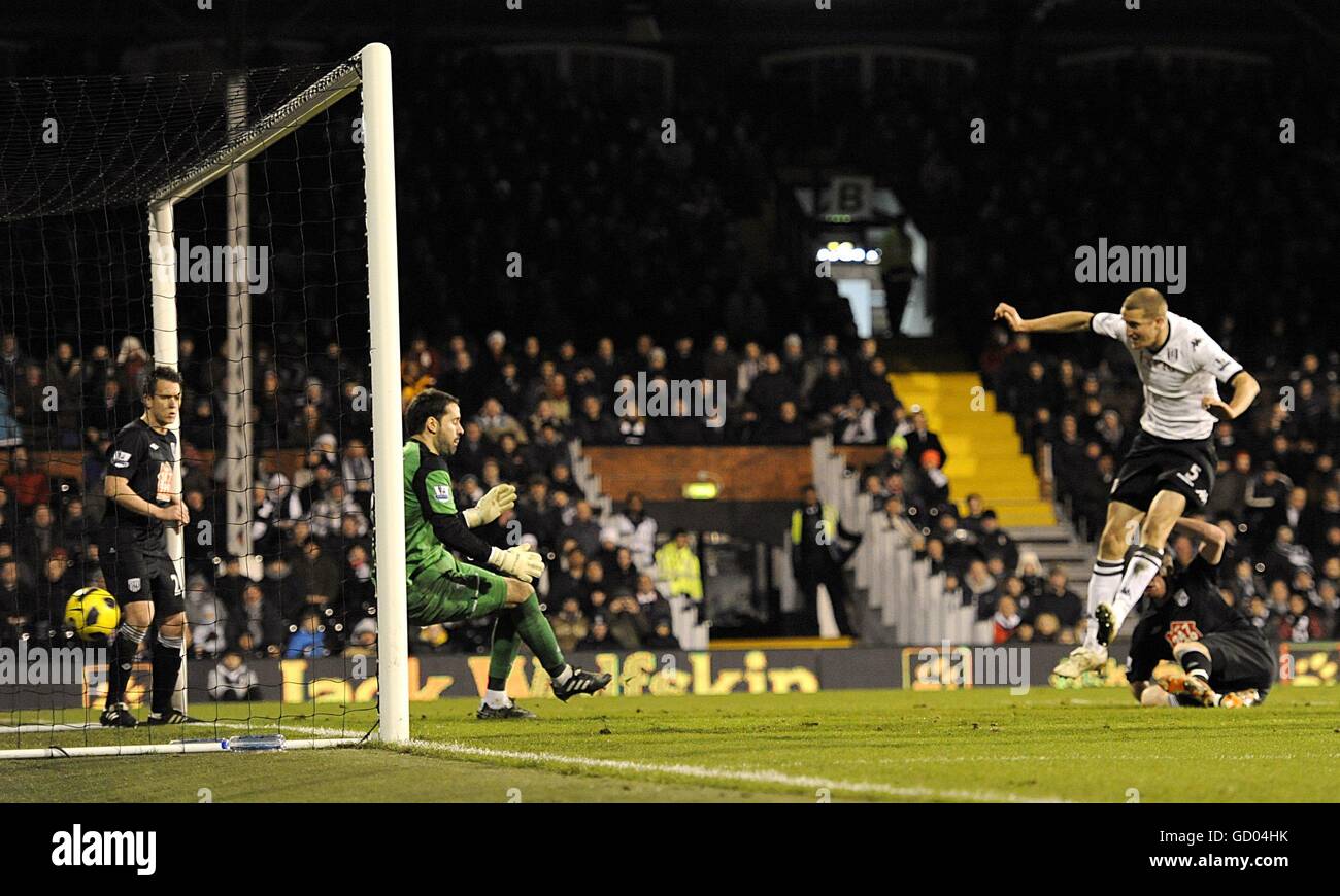 Il brede Hangeland di Fulham (a destra) spara oltre il portiere di West Bromwich Albion Scott Carson (al centro) e segna il terzo goal della sua squadra. Foto Stock