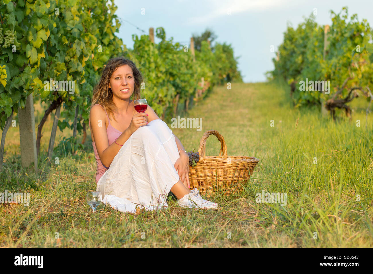 Ragazza con bicchiere di vino seduti in vigna Foto Stock