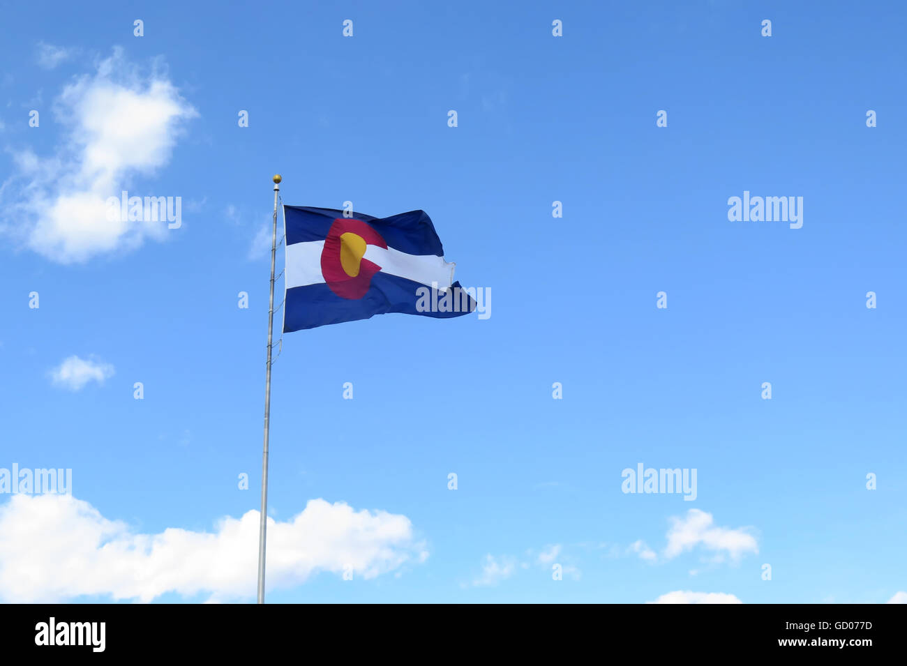 Il Colorado onde bandiera orgogliosamente contro un cielo azzurro con poche nuvole a distanza Foto Stock