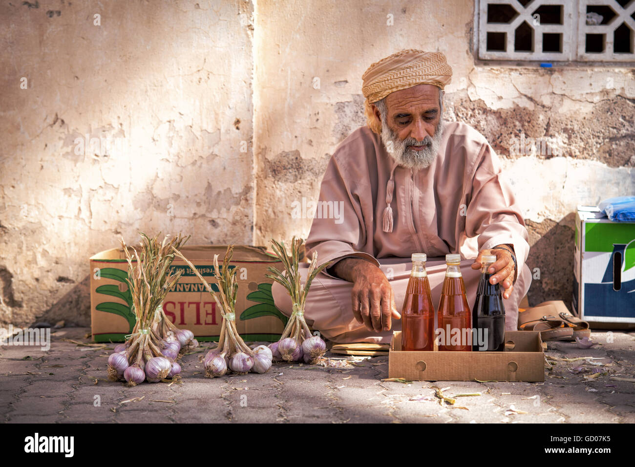 NIZWA, Oman - 24 Aprile 2015:Omani vecchio uomo vendita di miele e aglio al mercato tradizionale o souq di Nizwa, Oman Foto Stock