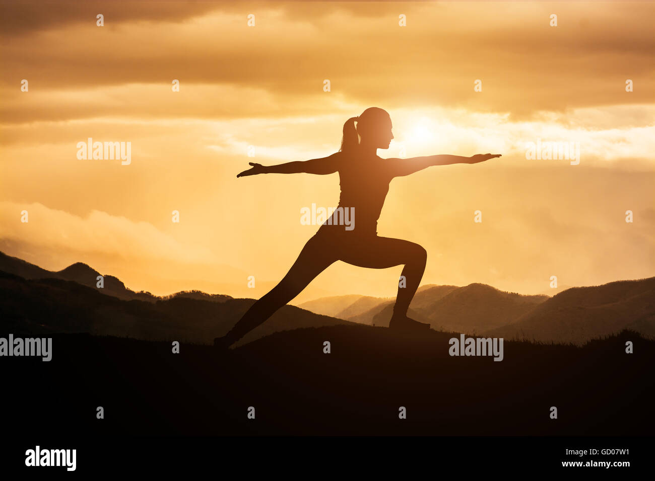 Giovane donna asiatica a praticare yoga warrior pongono al tramonto Foto Stock
