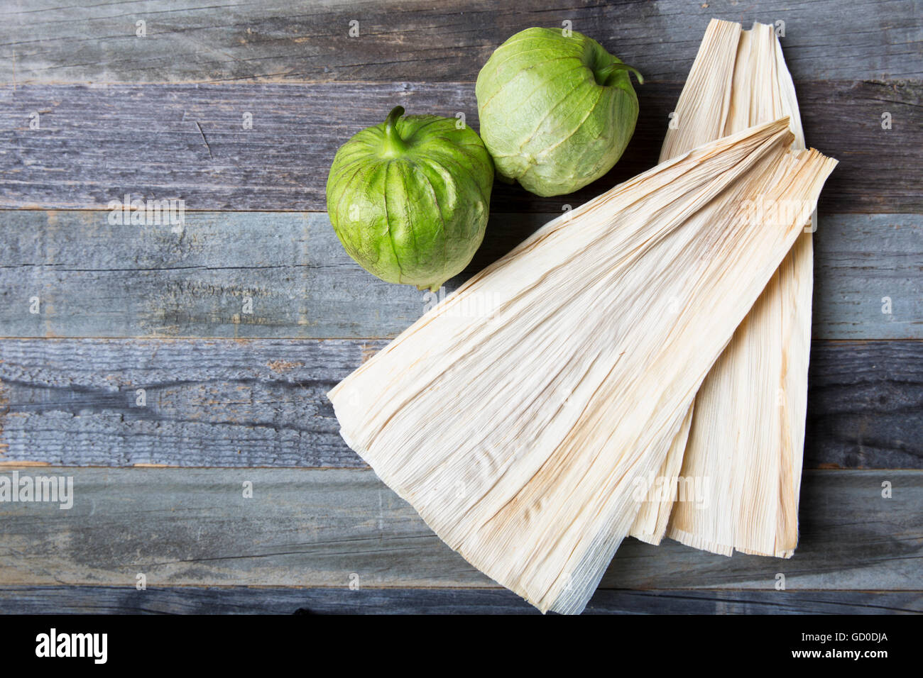 Tomatillos e bucce di mais su una superficie di legno con copia spazio. Foto Stock