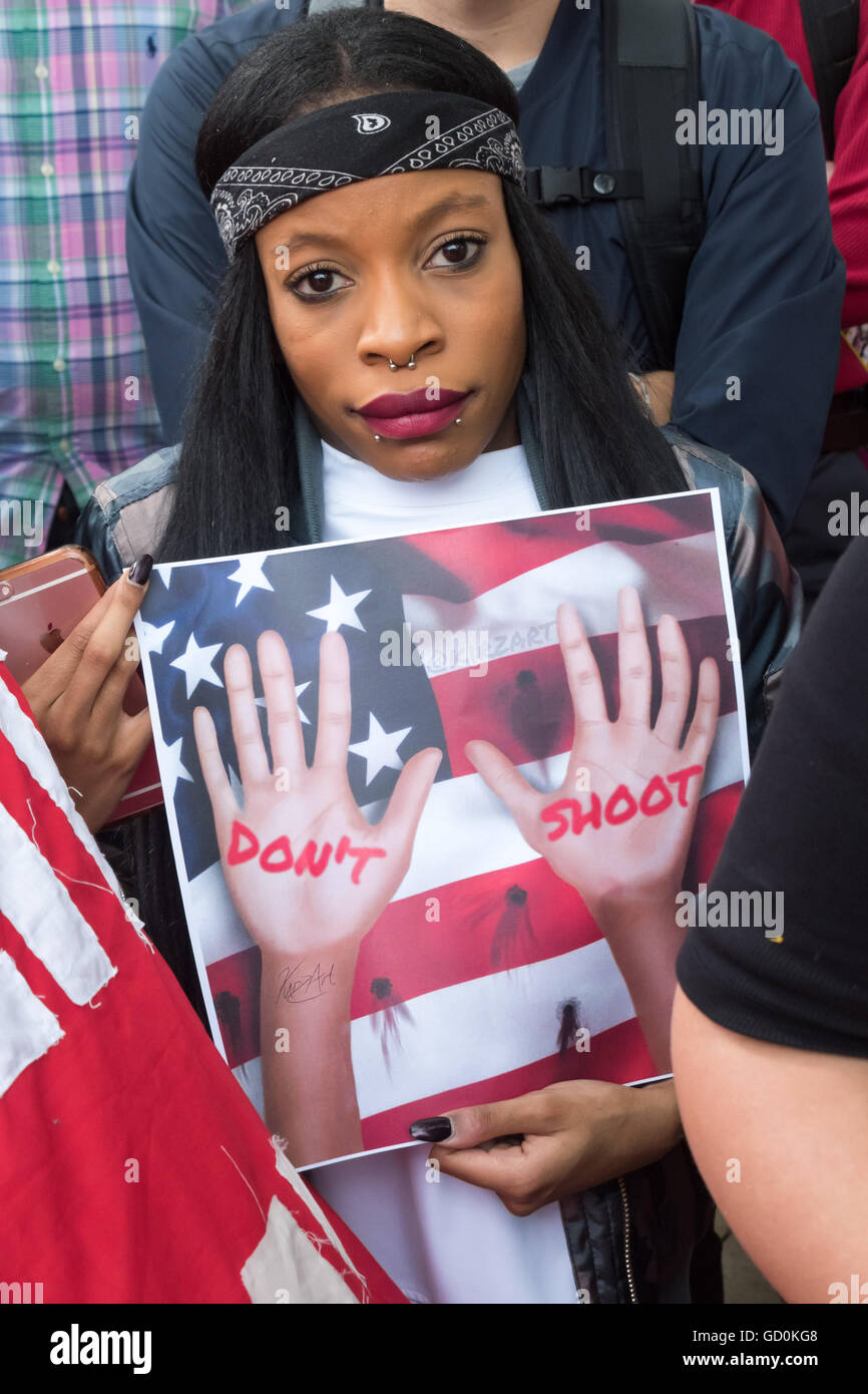 Londra, Regno Unito. Il 9 luglio 2016. Una donna che tiene un poster che mostra le mani alzate e il messaggio 'Non sparare' al rally in Brixton in memoria di Alton Sterling e Philando Castiglia e a mostrare solidarietà con quelli uccisi dalla polizia brutalità, sia negli Stati Uniti che qui nel Regno Unito. Ciò che era stato destinato a essere un breve rally prima di un passato marzo Brixton stazione di polizia e intorno la zona non ha mostrato alcun segno di finire come ho lasciato, con altoparlante altoparlante dopo prossimi all'aperto mike in Windrush Square di esprimere i loro sentimenti e la chiamata per l'azione positiva per la giustizia. Peter Marshall / Alamy Live News Foto Stock