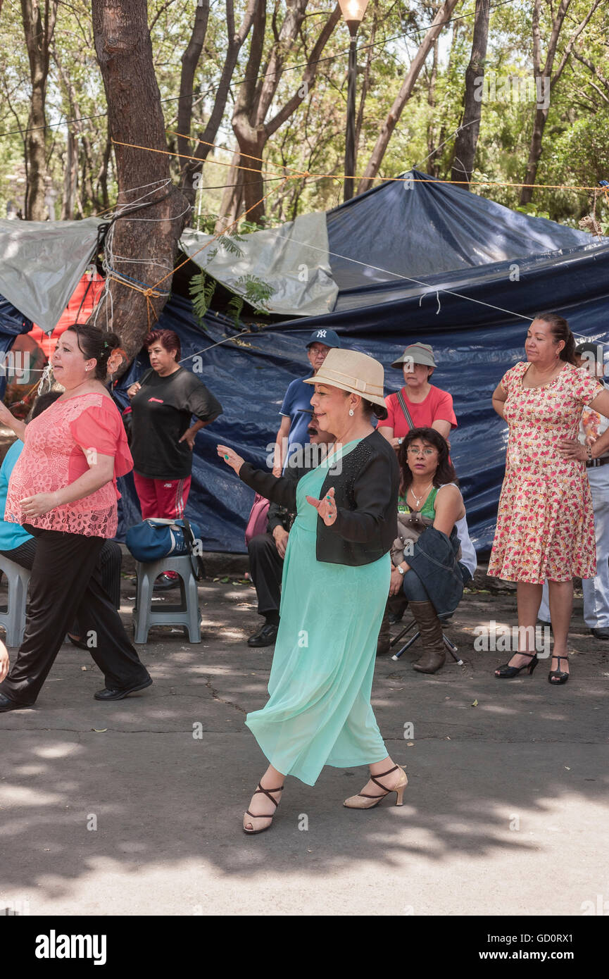 Città del Messico. 9 Luglio, 2016. Danzon aficionados raccogliere ogni sabato per socializzare e danza nella Plaza Ciudadela, un parco pubblico nel centro di Città del Messico. Attualmente, a causa di proteste da parte degli insegnanti che colpisce dal sud diversi stati messicani, il parco è occupata e la sua normalmente aperte aree coperte con tende e teloni. Nonostante la mancanza di spazio, i ballerini di praticare le loro mosse nel mezzo di una strada che attraversa il parco, come insegnanti e osservare i passanti. Credito: Keith Dannemiller/Alamy Live News Foto Stock