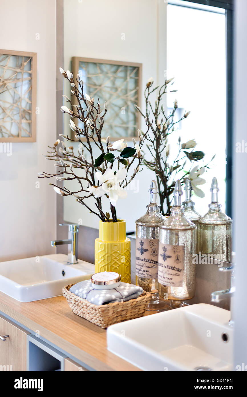Lussuoso bagno con specchio e bottiglie di profumo accanto a un vaso di  fiori accanto al rubinetto di argento e bianco con dissipatore di  asciugamani Foto stock - Alamy