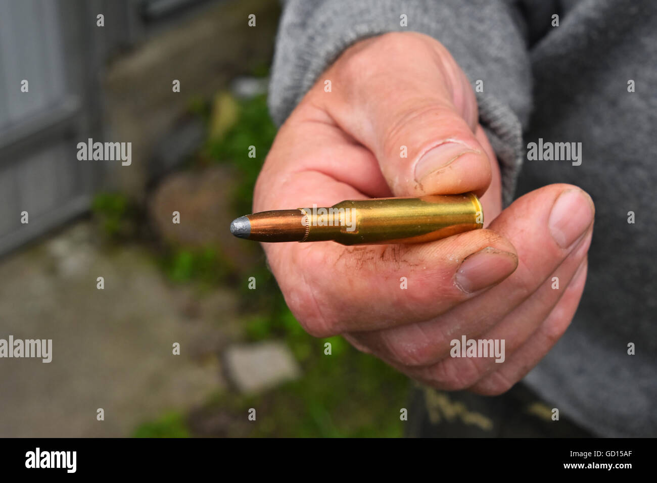 Old man mano che tiene e mostra uno 7,62 mm munizioni calibro bullet Foto Stock