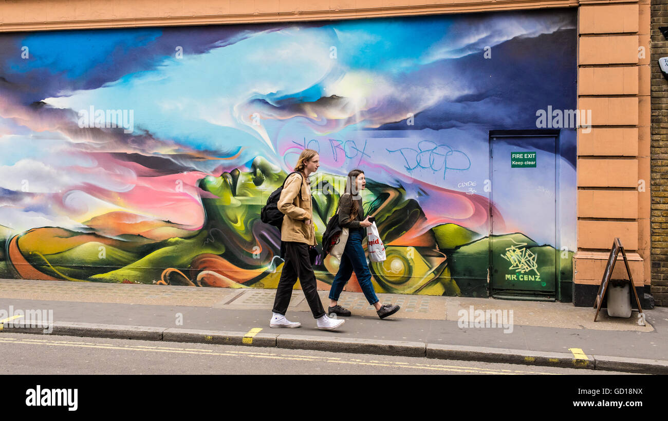 Hipster giovane a piedi nella parte anteriore di un graffiti in una strada di Soho, una zona alla moda di Londra famosa per i ristoranti e club Foto Stock