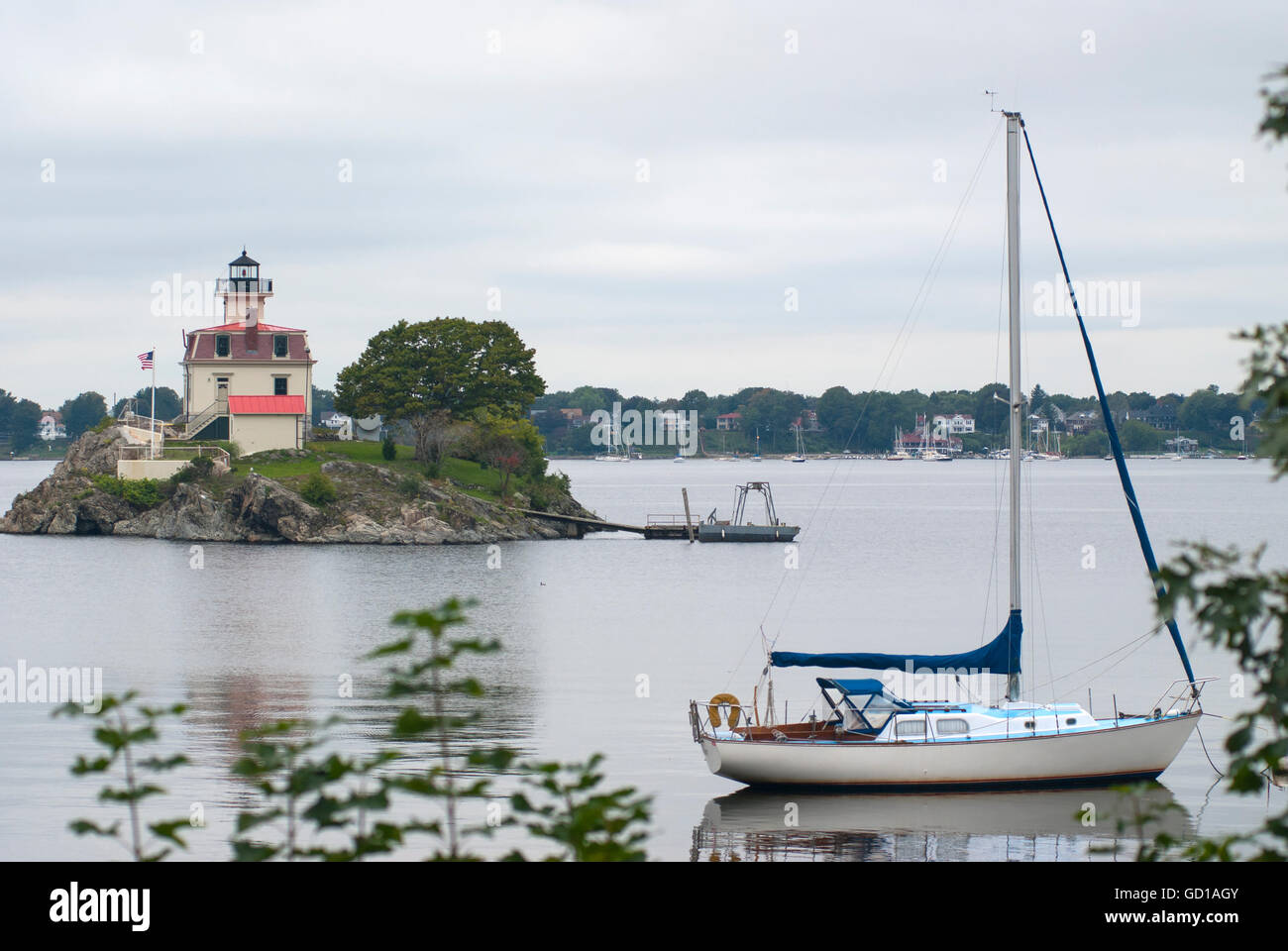 Barca a vela ancorata da rocce Pomham faro in un giorno nuvoloso nel Rhode Island. Foto Stock