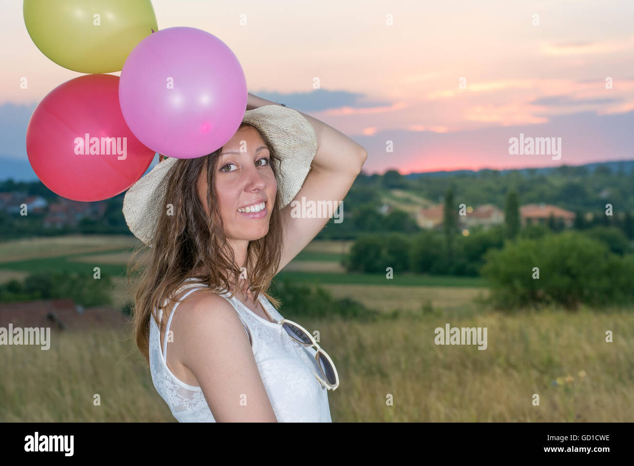 Giovane donna azienda palloncini a romantico tramonto Foto Stock