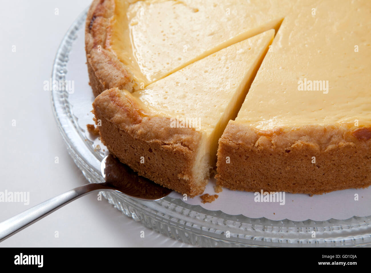 Torta di formaggio su una lastra di vetro e un pezzo di torta torta sul server Foto Stock