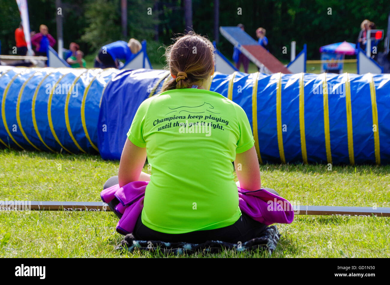 Champions continuare a giocare finché non è giusta. Un gestore di cane guardando un concorso corso essendo impostato in agilità Uulu cup. Foto Stock