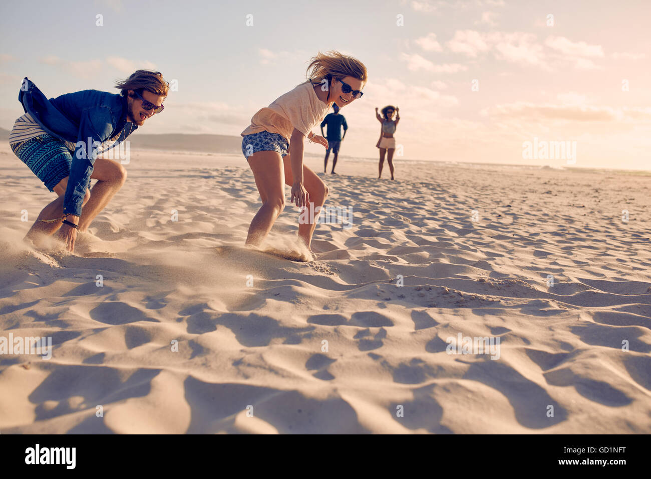 Due giovani amici con cui gareggiare in una corsa su di una spiaggia di sabbia. Giovane uomo e donna eseguendo una corsa sulla spiaggia. Foto Stock
