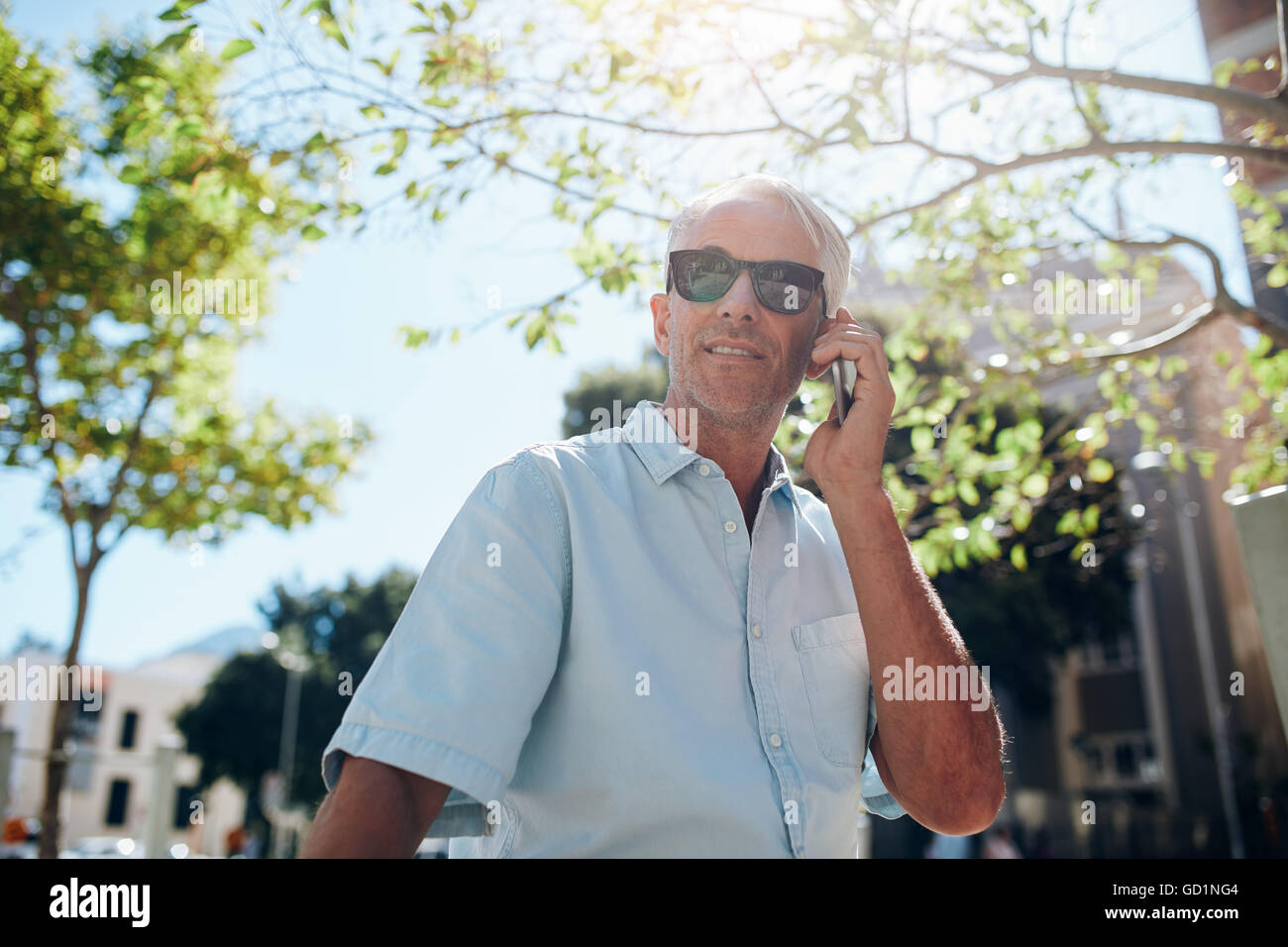 Senior uomo caucasico di relax all'aperto nella città e parlando al telefono cellulare. Tourist al di fuori della città di effettuare una chiamata Foto Stock