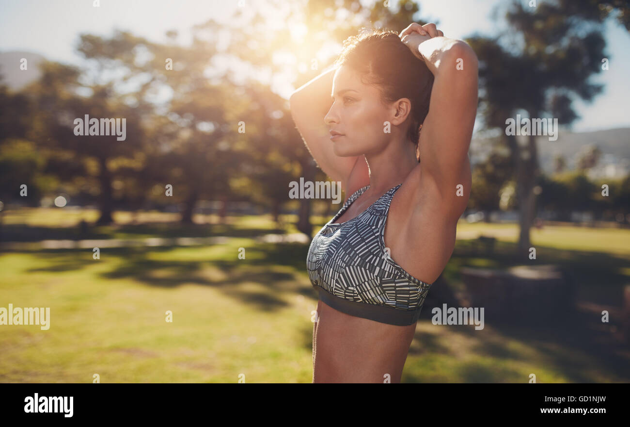 Lato ritratto di muscolare di giovane donna che esercitano presso il parco. Donna ispanica che lavora fuori all'aperto in una giornata di sole. Foto Stock