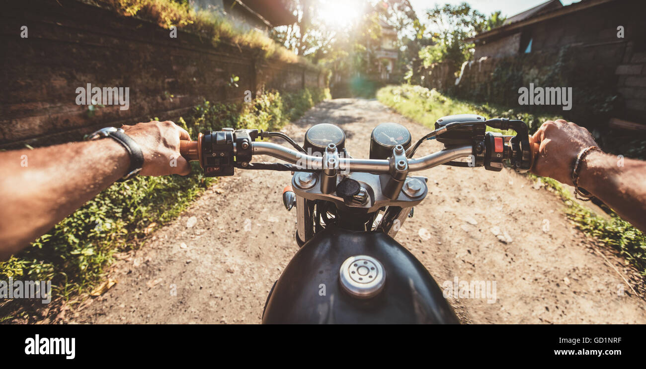 Pilota moto di guida su una strada rurale. Il punto di vista delle riprese con focus moto manubrio e man mano. Foto Stock
